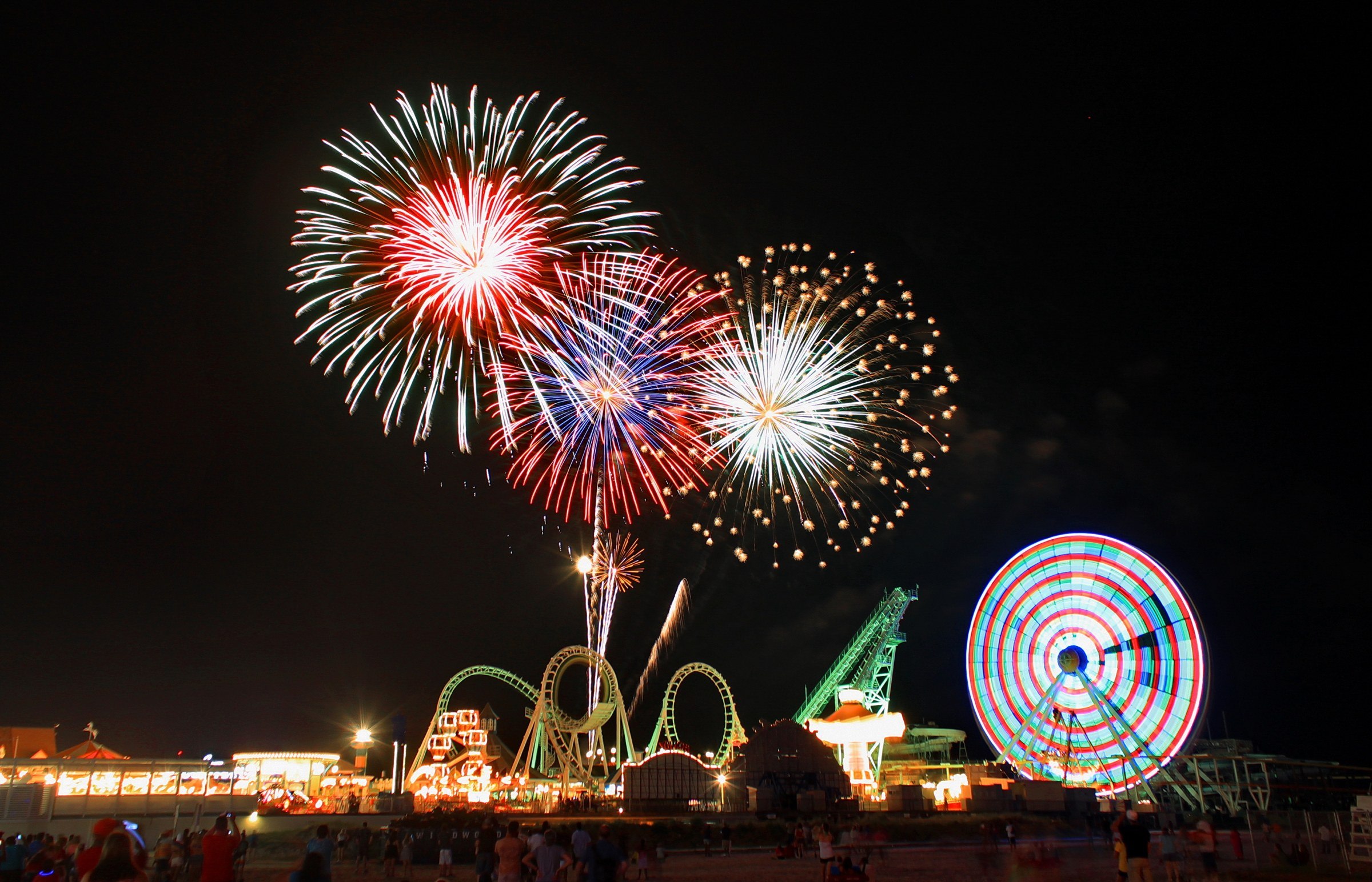Fireworks in the sky over amusement parkDescription automatically generated