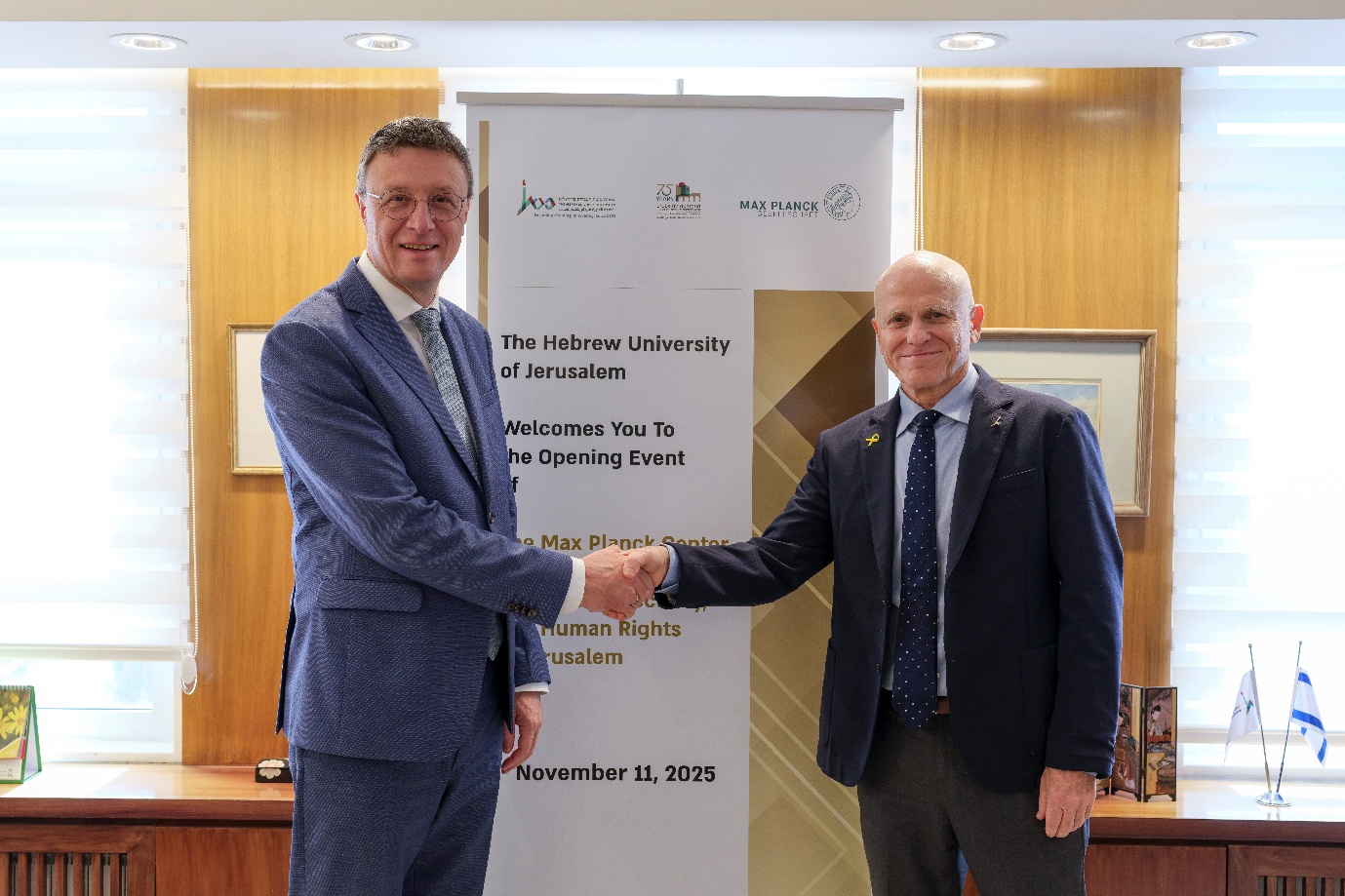 Two men shaking hands in front of a signAI-generated content may be incorrect.