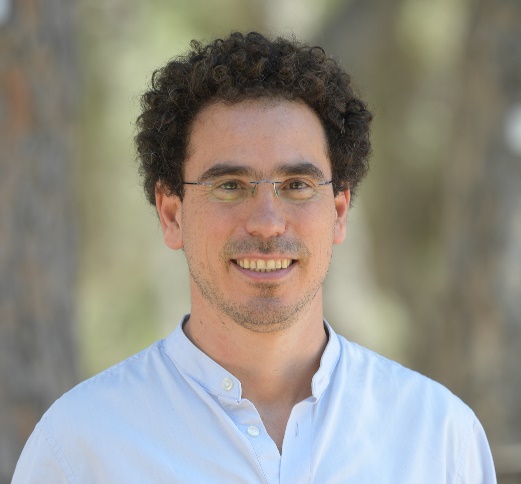 A person with curly hair wearing glassesAI-generated content may be incorrect.
