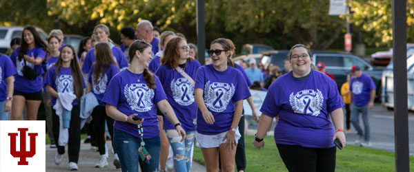 Four people in purple T-shirts walk
