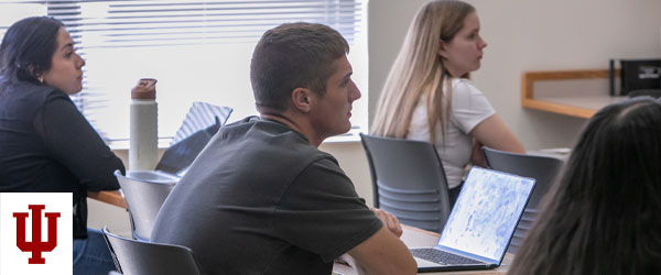 a man and a woman sit at desks in a classroom