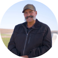 A person with a mustache and cap Description automatically generated