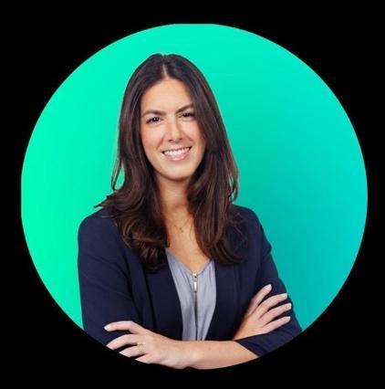 A person with long, curly hair and a professional attire, holding their hands out, against a bright green background.AI-generated content may be incorrect.