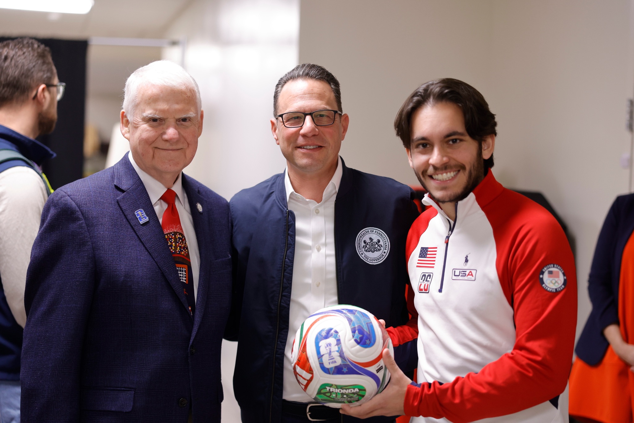 Three men posing for a photo with a soccer ball